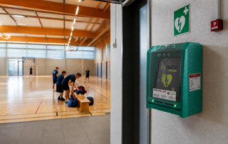 Défibrillateur HeartSine dans un coffre vert installé dans un gymnase